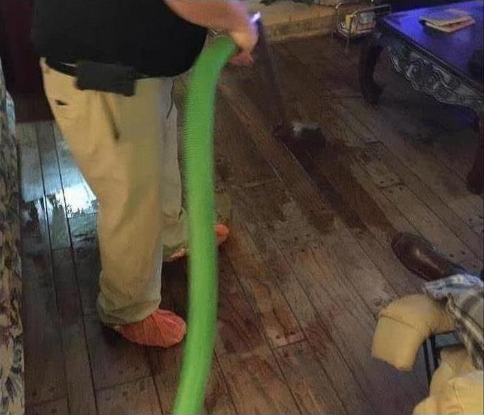 Servpro technician using professional equipment to remove excess water from a residential home. 